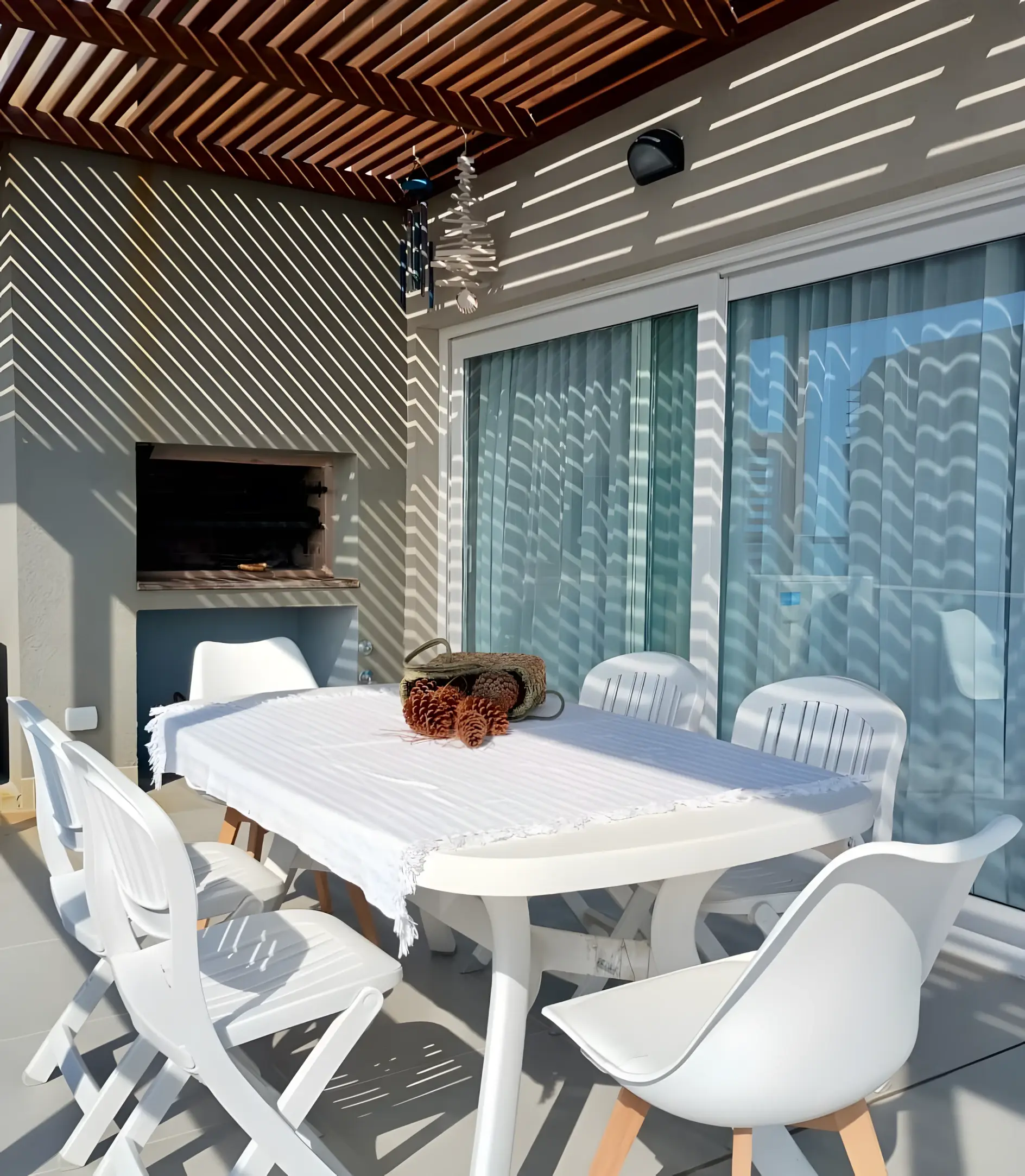 Balcón techado con parrilla y mesa, visto desde el interior