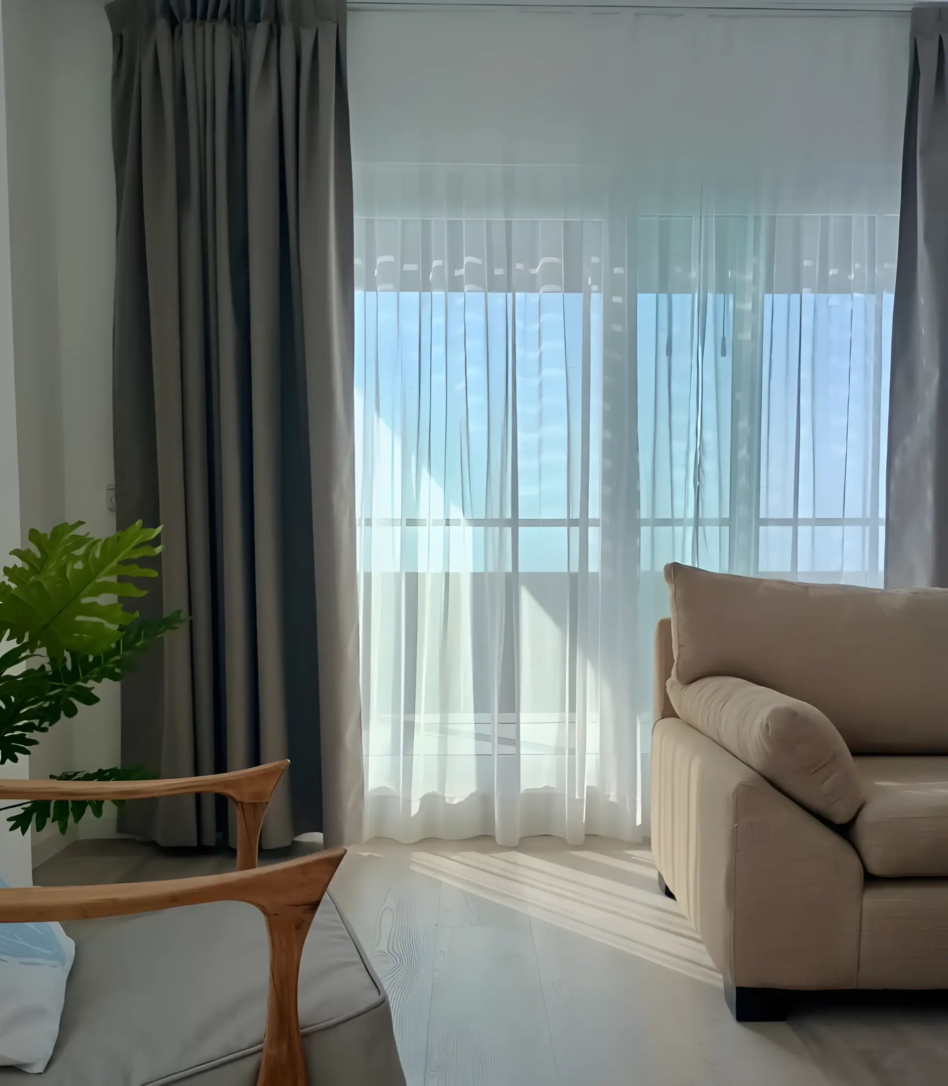 Living con cortinas claras y ventanal de piso a techo