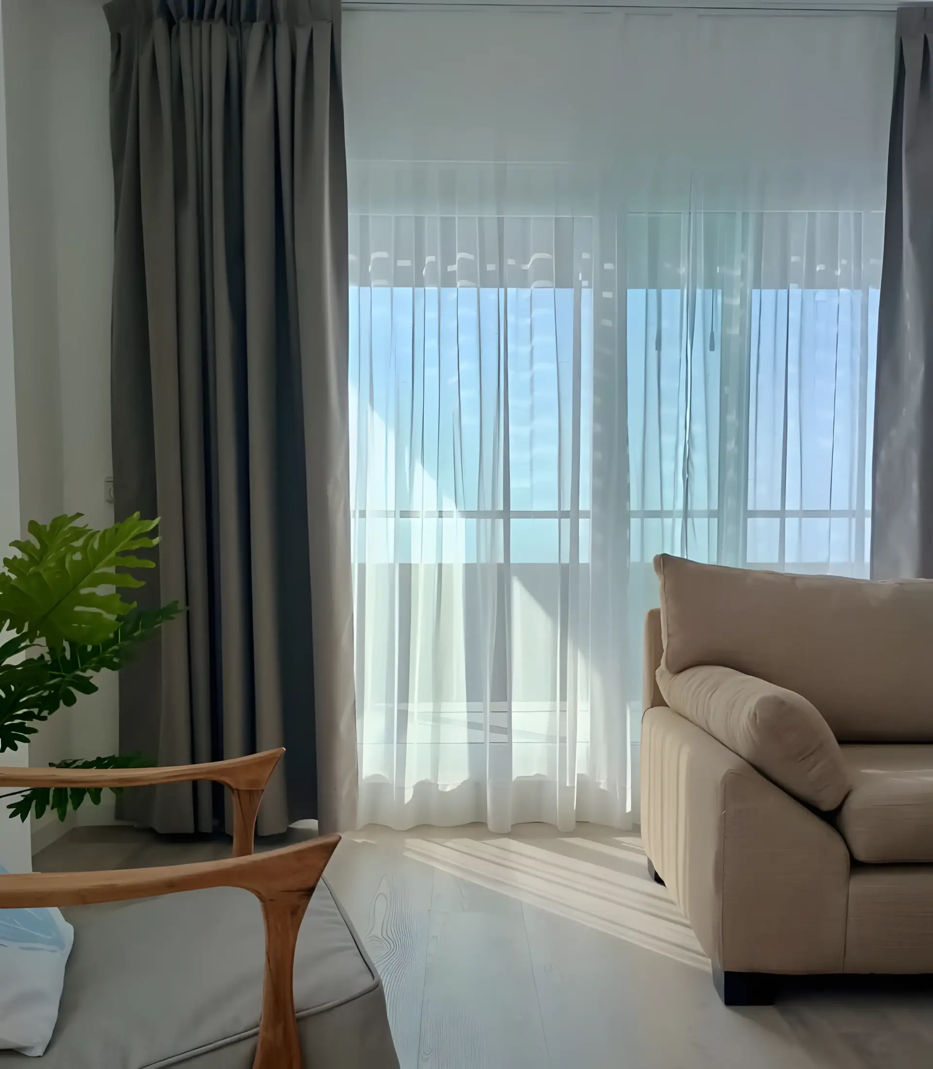 Living con cortinas claras y ventanal de piso a techo